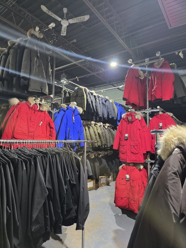 OSC parkas and winter jackets displayed on racks inside the factory warehouse.